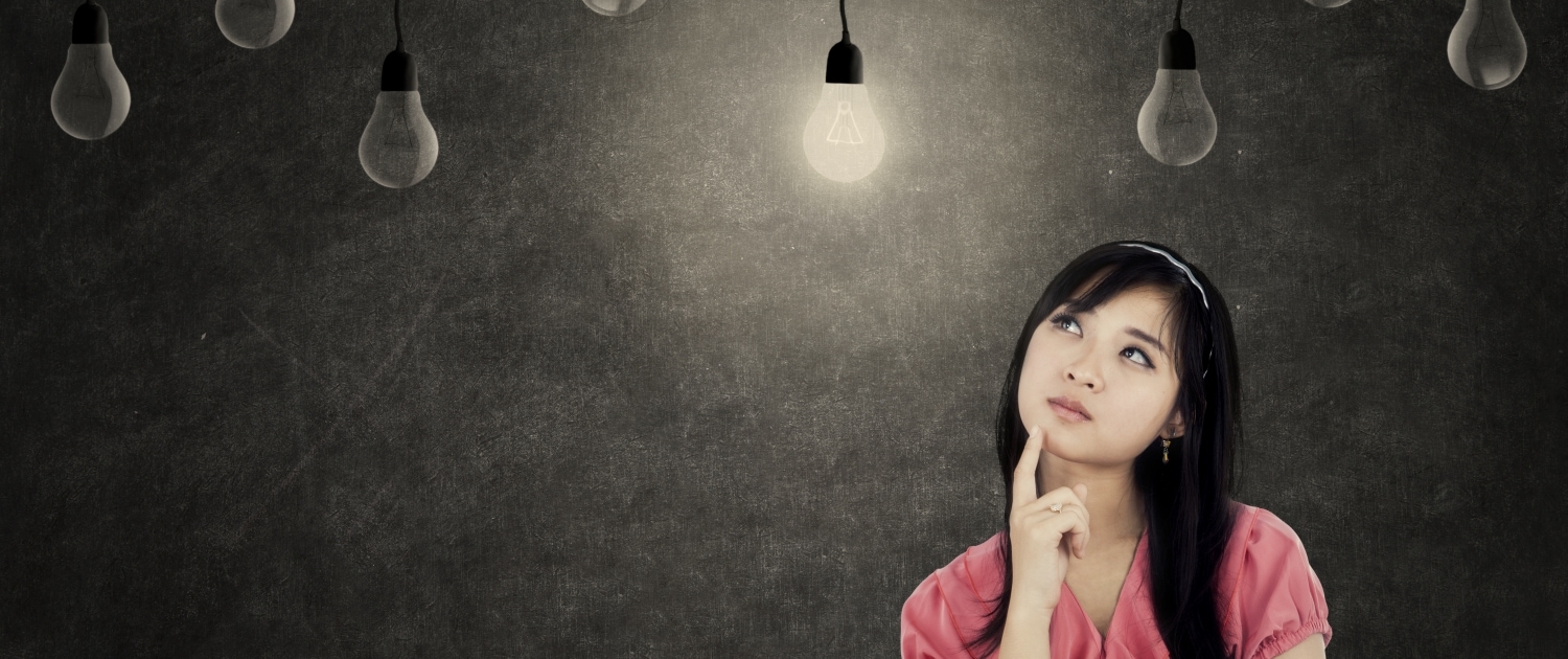 Thoughtful young businesswoman thinking idea while looking up with light bulbs